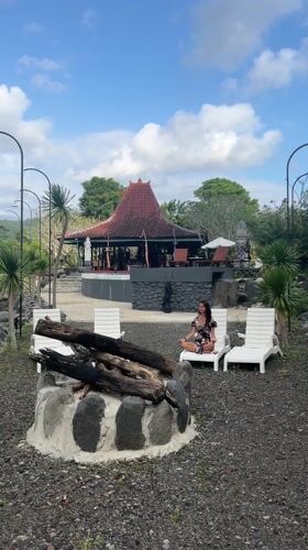 Woman meditates at Balinese pavilion near flowing river in Sidemen