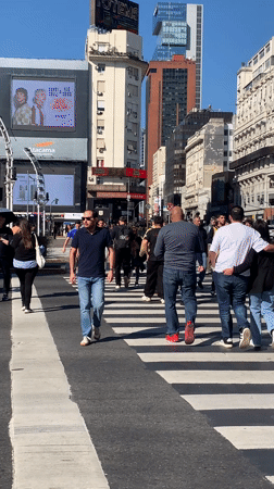 Pedestrians cross street in Buenos Aires during evening hours