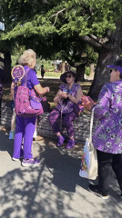 Purple-clad women gather at Bar Montenegro plaza near tour buses