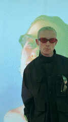 Person with blonde hair, red sunglasses spotted near projection wall