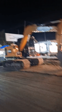 Excavator parked near roadside eatery in Lhokseumawe, Indonesia