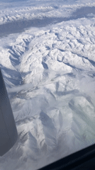 Passenger films snowy mountains, town from airplane near Shymkent
