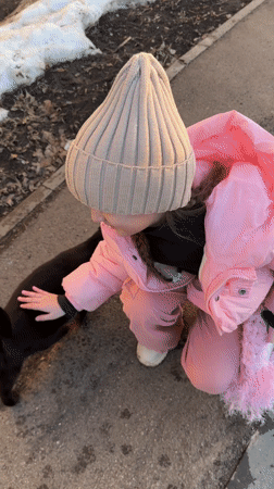 Children pet stray cat on wet street in Russia