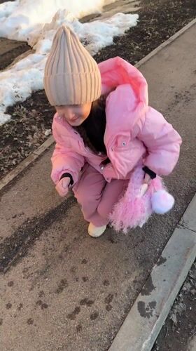 Children pet stray cat on wet street in Russia