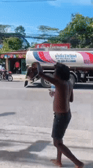 Barefoot on a Ko Samui sidewalk, arm raised near traffic light