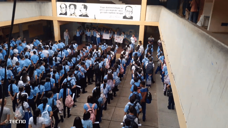 Students gather for assembly with sign-holders in Venezuelan school courtyard