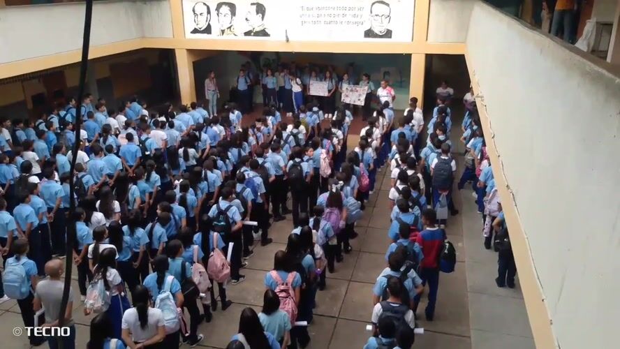 Students gather for assembly with sign-holders in Venezuelan school courtyard