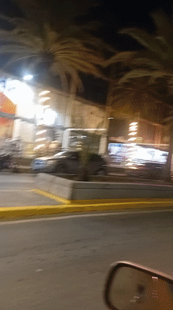 Night drive through Juangriego street with lit storefronts