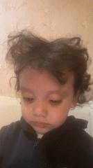 Toddler in black hoodie plays mobile game, shows various expressions