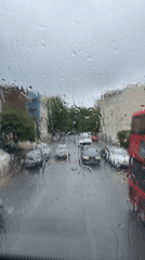 Heavy rainfall hits London streets, cars navigate wet conditions