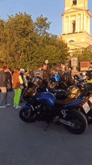 Motorcycle gathering near waterfront building during sunset hours