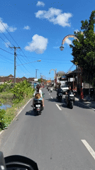Moped riders travel through Gianyar street in early morning