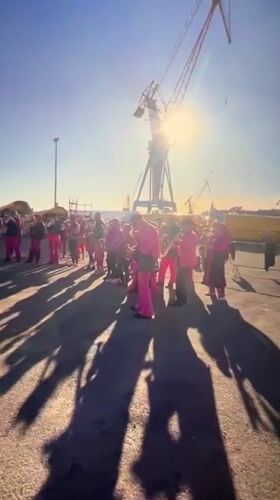 Pink-suited musicians perform outdoors in industrial Brest, France
