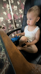 Toddler plays with toy truck in office chair