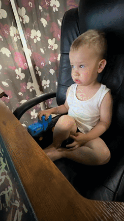 Toddler plays with toy truck in office chair