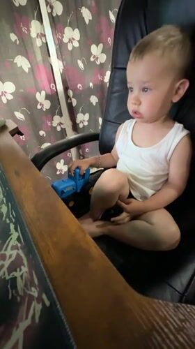 Toddler plays with toy truck in office chair