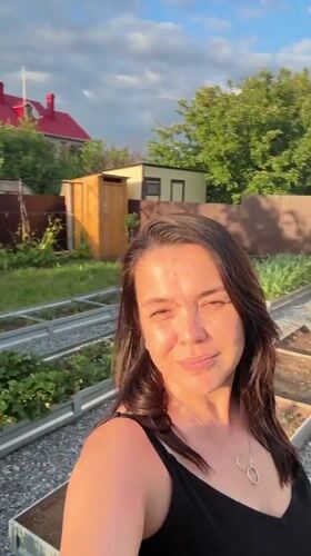 Woman documents afternoon garden activities with pet in Oktyabrsky