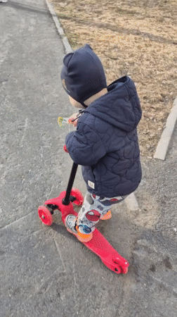 Child rides red scooter in Tobolsk winter gear