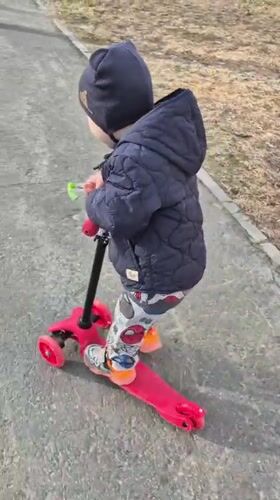 Child rides red scooter in Tobolsk winter gear