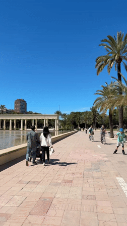Couple strolls with stroller through sunny València park