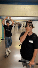Two men ride scooters through indoor corridor in Barcelona
