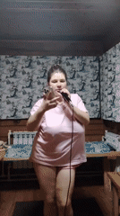 Woman leads karaoke session in wooden room, Russia