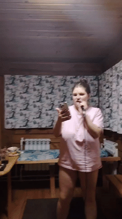 Woman leads karaoke session in wooden room, Russia