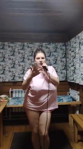 Woman leads karaoke session in wooden room, Russia