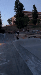 Shirtless skateboarder performs tricks at Madrid skate park at dusk