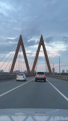 Evening drive through city streets toward a cable-stayed bridge