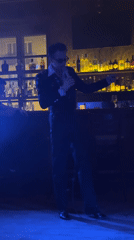 Singer performs in dark suit at atmospheric bar venue