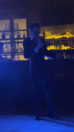 Singer performs in dark suit at atmospheric bar venue