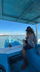 Person sits on boat watching water in Indonesia