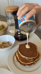 Person pours condensed milk on pancakes in Tel Aviv