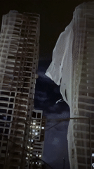 Construction site shows wind-damaged protective netting on tall buildings
