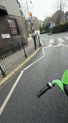 Lime scooter rider travels London streets in afternoon