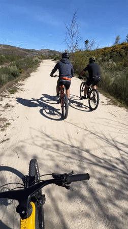 Three cyclists ride mountain bikes on Portuguese dirt road