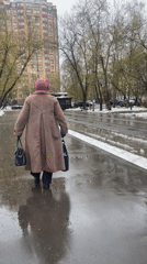 Person in coat walks on wet pavement in Khimki