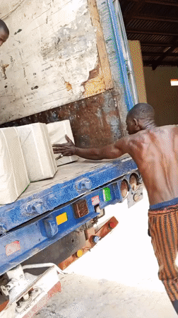 Workers unload wrapped packages from truck in Pasere, Nigeria