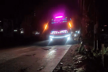 Decorated buses and roadside activity on a Pasirsari night road