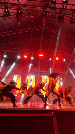 Cowboy-hat dancers perform in red and black on a spotlit stage