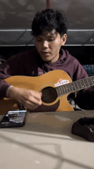 Street musician performs acoustic guitar in Lhokseumawe alleyway