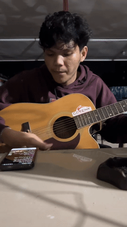 Street musician performs acoustic guitar in Lhokseumawe alleyway