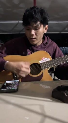 Street musician performs acoustic guitar in Lhokseumawe alleyway