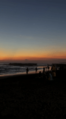 Sunset draws beachgoers to black sand shores in North Kuta
