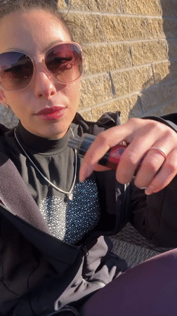 Woman vapes outdoors during sunny Liverpool afternoon