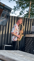 Street saxophonist performs near restaurant terrace in Saint-Galmier