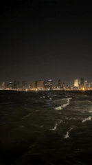 Tel Aviv skyline captured at night with ocean waves
