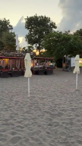 Burgas beach at dusk: umbrellas, cargo ships, and a full moon