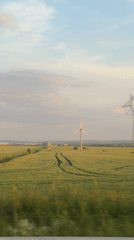 Train passenger captures rural Bulgarian landscape with wind turbine